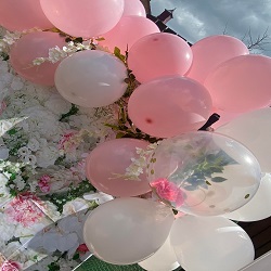 bunch of pink and white balloons with floral decorations against a background of faux flowers ideal for party celebrations and events